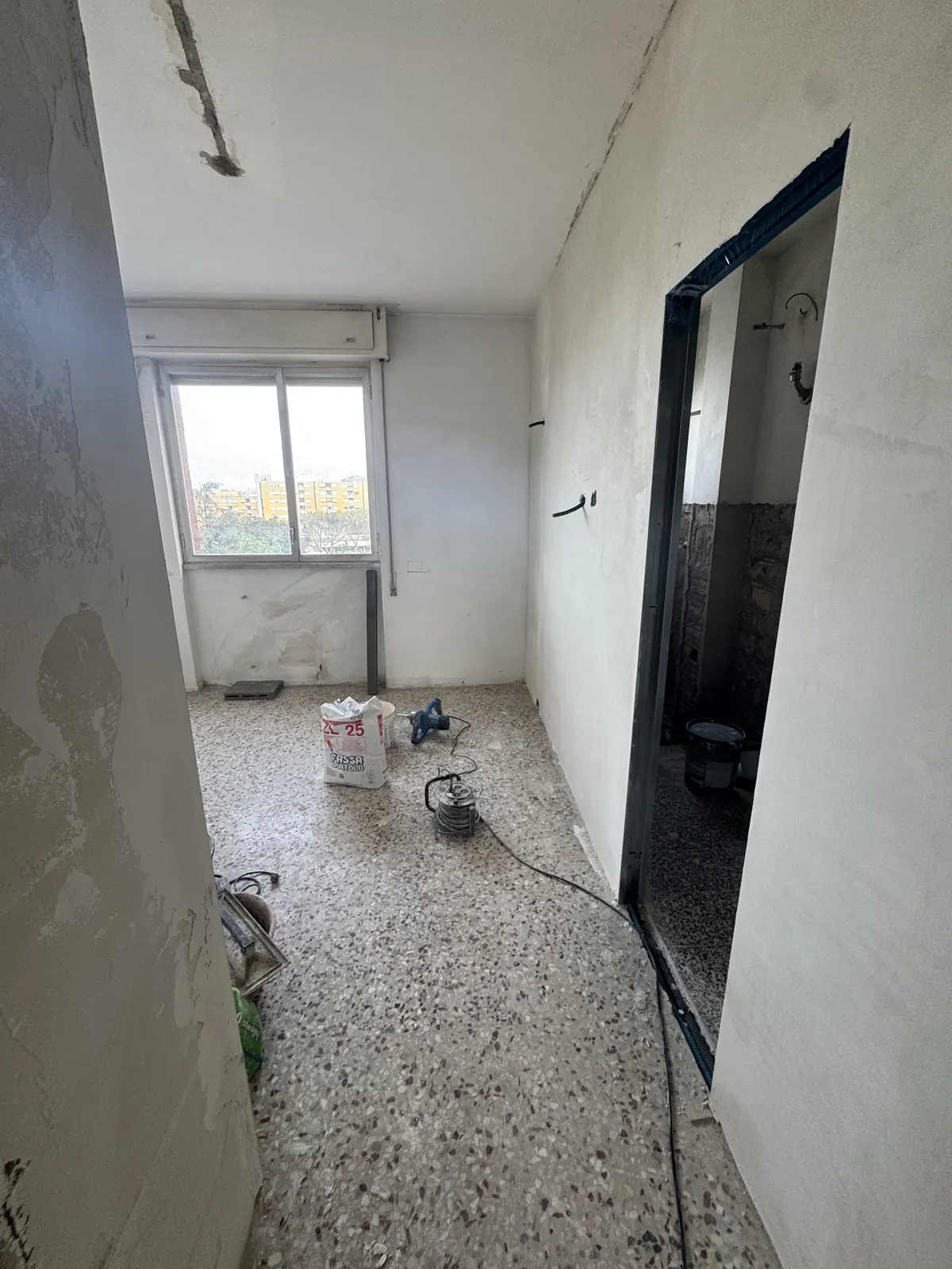 Stanza in cantiere con un nuovo vano porta e materiali a terra