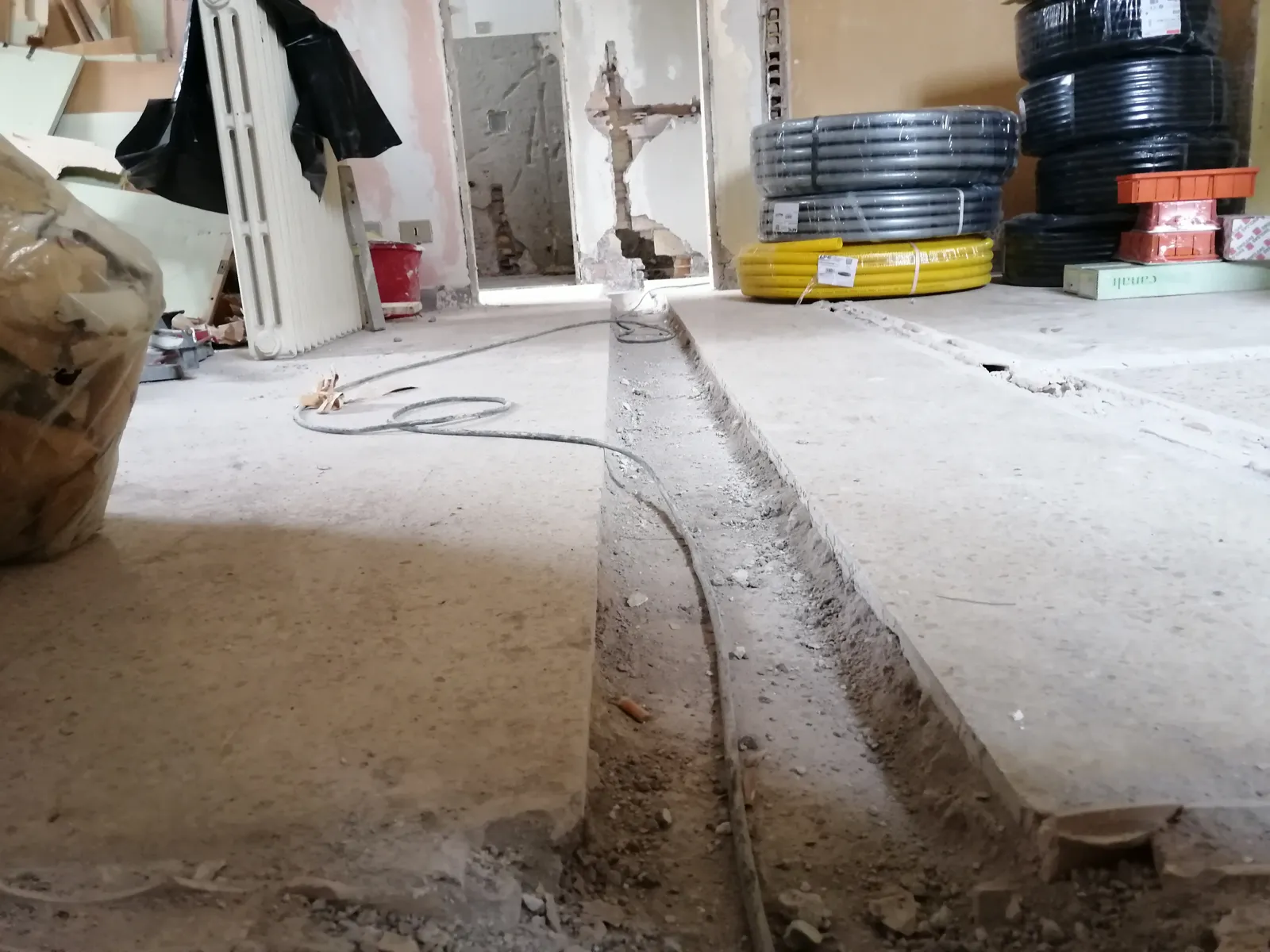 Tracce a pavimento e rotoli di tubazioni per i nuovi impianti in un appartamento in ristrutturazione