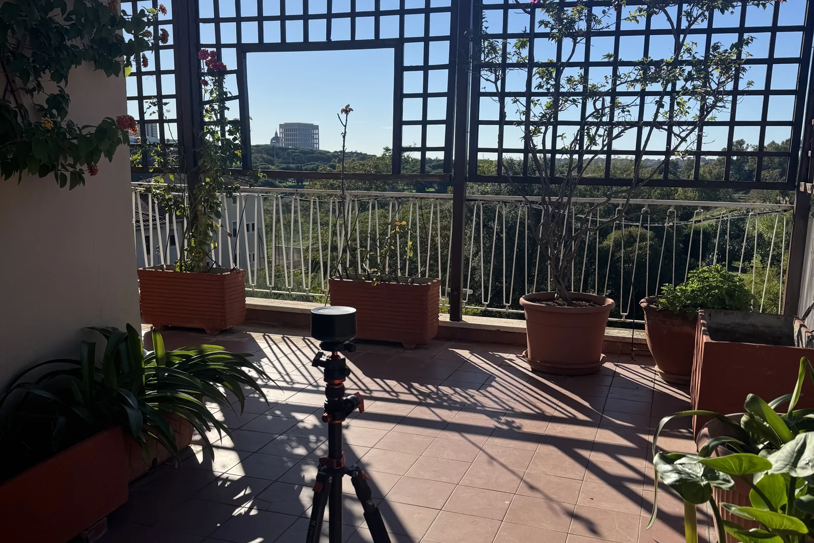 Laser scanner su treppiede in una terrazza a Roma durante un rilievo, con il Colosseo Quadrato dell'EUR sullo sfondo